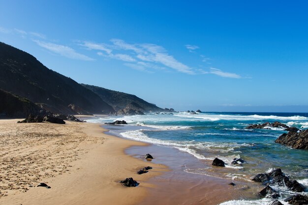 Beautiful scenery of a beach surrounded by hills under the clear sky