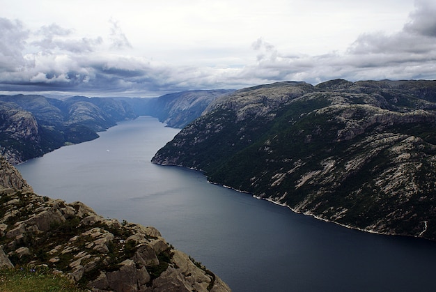 Free photo beautiful scenery of famous preikestolen cliffs near a lake under a cloudy sky in stavanger, norway