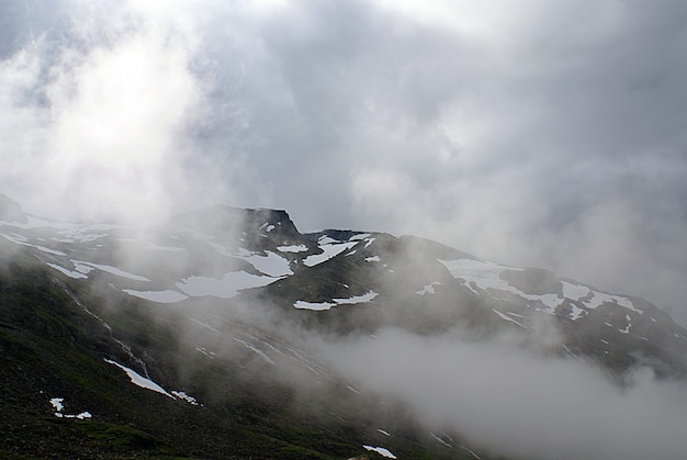 Free Photo beautiful scenery of high rocky mountains covered with snow enveloped in fog in norway