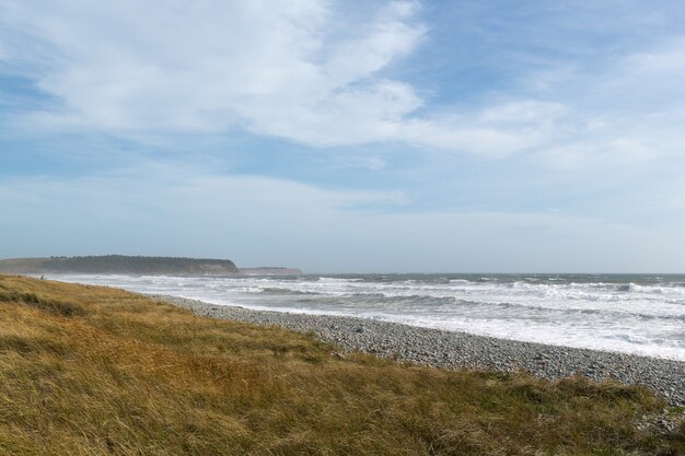 Beautiful scenery of ocean waves moving towards the shore under the cloudy sky