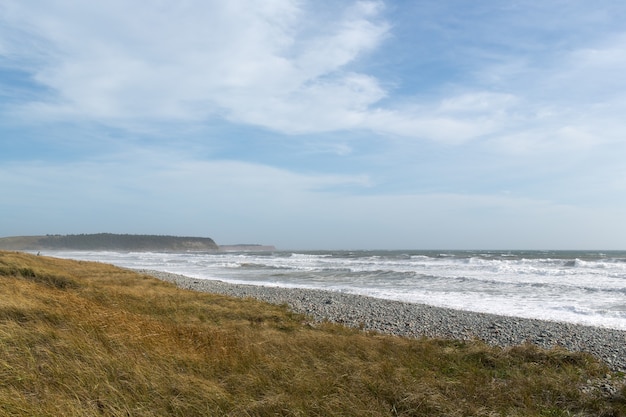 Beautiful scenery of ocean waves moving towards the shore under the cloudy sky