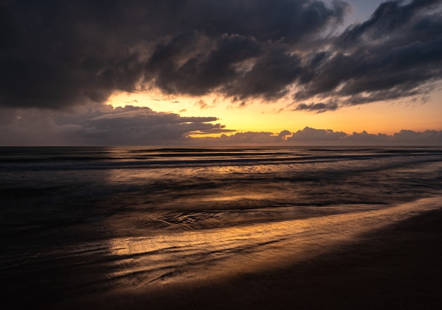 Beautiful scenery of a wavy sea under a cloudy sky at sunrise