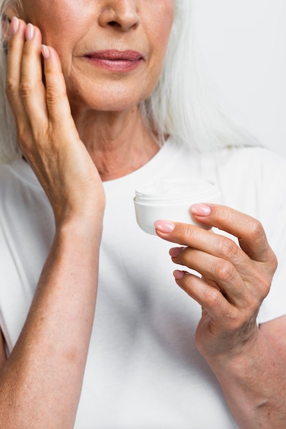 Beautiful senior woman applying skin care