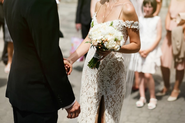 Beautiful sexual young bride in white vintage dress and handsome groom hold each other hands