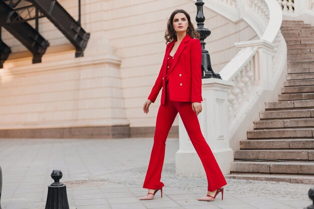 Beautiful sexy rich business style woman in red suit walking in city street, spring summer fashion trend