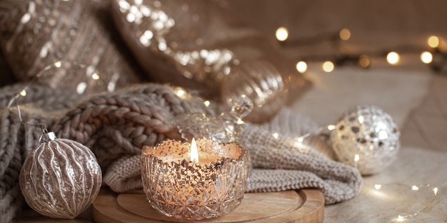 Beautiful shiny silver christmas decor and burning candle close up. Cozy winter atmosphere.