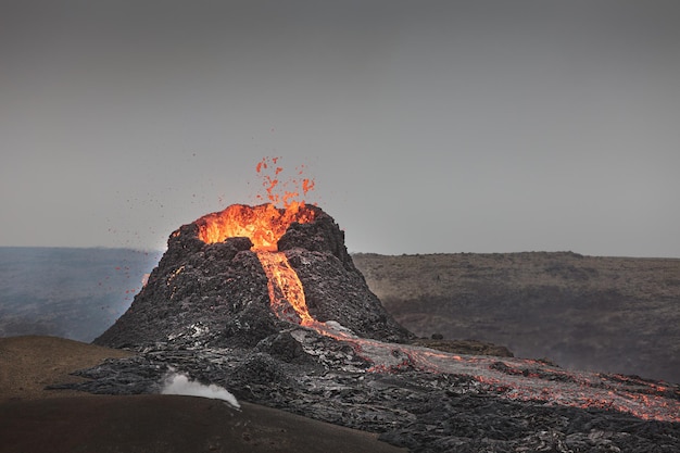 Free photo beautiful shot of an active volcano with flowing lava and smoke under a clear sky