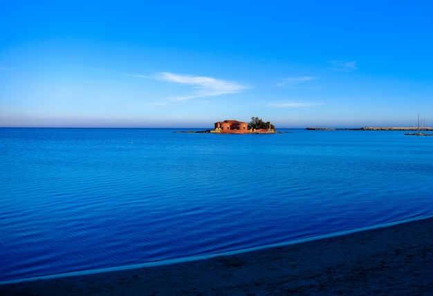 Free photo beautiful shot of a big house in the middle of the sea under a blue sky