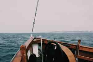 Free photo beautiful shot of a bow of the boat on the sea with hills and a cloudy in the background