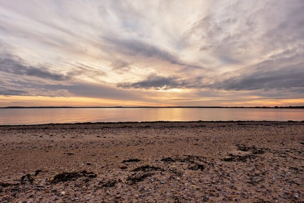 Beautiful shot of a calm ocean with a scenery of sunset in a cloudy blue sky