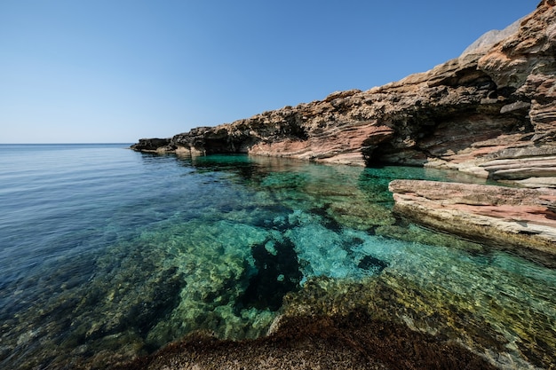 Free photo beautiful shot of clear water near a rocky cliff on a sunny day