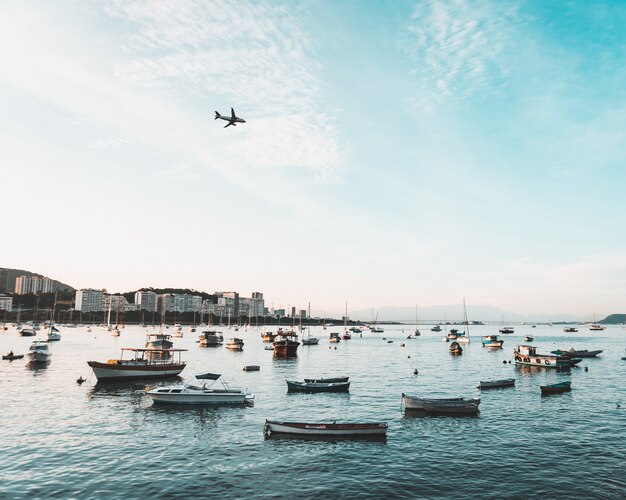 Free Photo beautiful shot of coast of an urban coastal city with many boats and an airplane flying in the sky