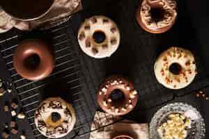 Free photo beautiful shot of delicious donuts covered in the glaze and chocolate pieces on a black table