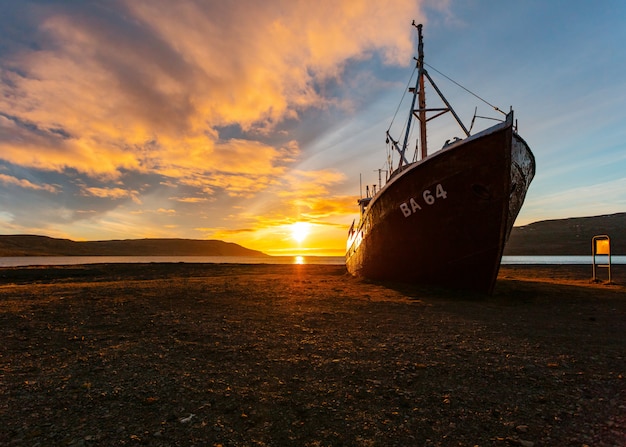 Free Photo a beautiful shot of a fishing boat approaching the beach at sunrise