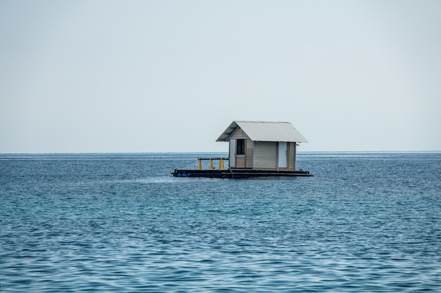 Free Photo beautiful shot of a floating house in a blue ocean with a clear white sky in the