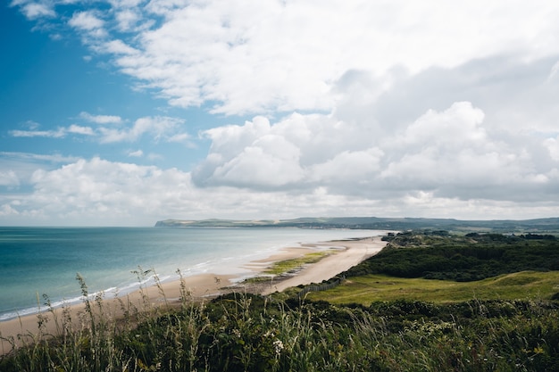 Free photo beautiful shot of a grassy field near the beach shore under a cloudy sky in france