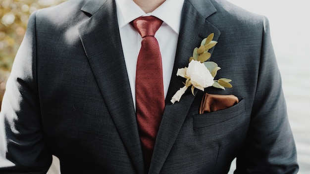 Free photo beautiful shot of the groom with a white flower on a suit