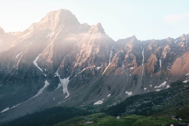 Free Photo beautiful shot of a house on a grassy hill with mountains and a clear sky