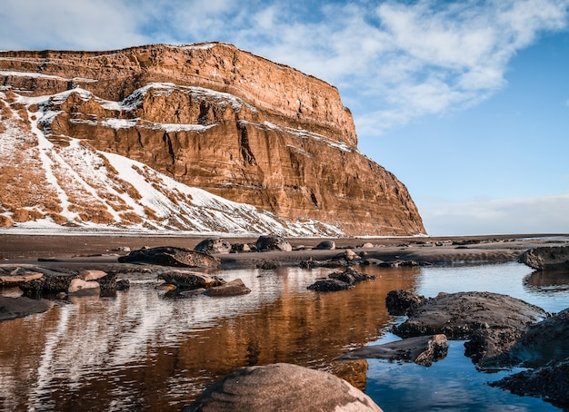 Beautiful shot of a lake in front of a snowy mountain with blue sky