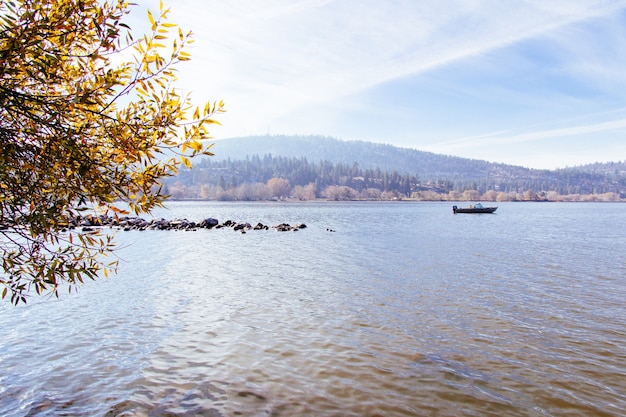 Beautiful shot of a lake with a boat sailing on it with a sunny sky