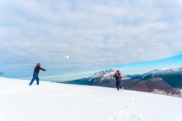 Beautiful shot of the male and female playing with snowballs in Oiertzun, Basque, Spain