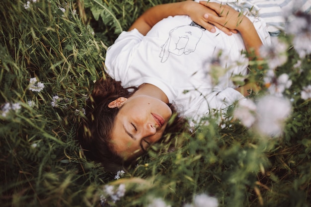 Free photo beautiful shot of a model laying down in a daisy field with her eyes closed