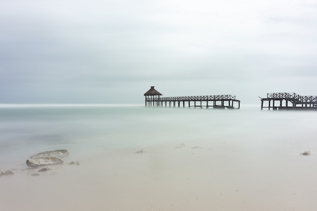 Beautiful shot of an ocean or a sea coast with a wooden small bridge under the blue sky