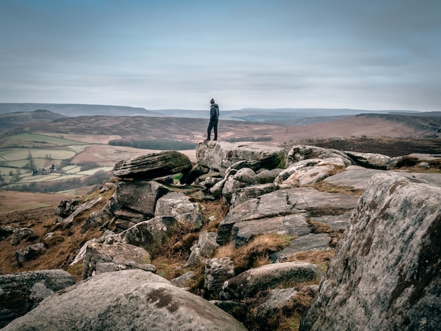 Free Photo beautiful shot of a person standing on the rocks and looking at the valley in the distance