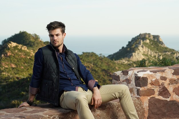 Beautiful shot of a pretty male sitting comfortably in front of his house