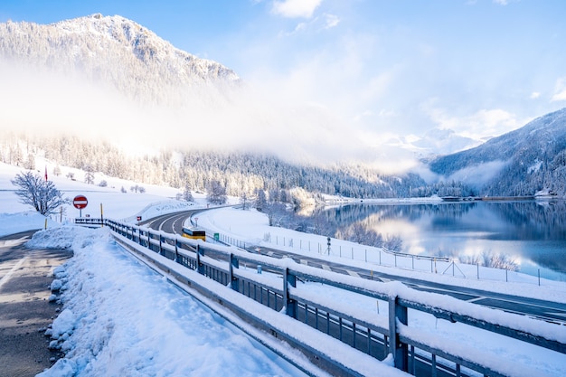 Beautiful shot of a road near a lake surrounded by snow-covered mountains