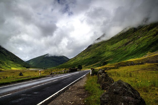 Beautiful shot of the road surrounded by mountains under the cloudy sky