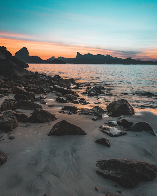 Free Photo beautiful shot of the rocky coast of the sea at sunset with amazing blue sky