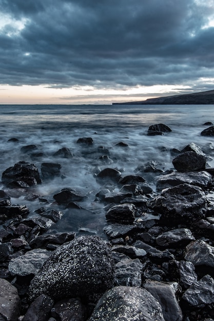 Beautiful shot of rocky coast of the sea with amazing water texture and breathtaking cloudy grey sky