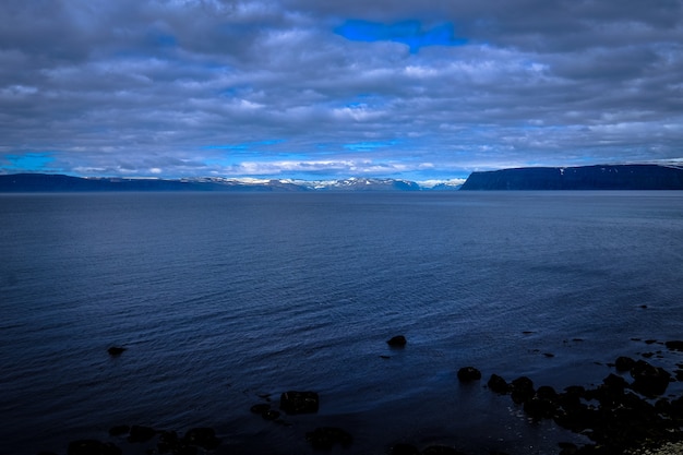 Beautiful shot of a sea and mountains in the distance under a cloudy sky