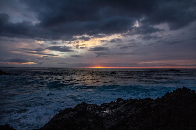 Free Photo beautiful shot of sea waves near rocks under a cloudy sky at sunset