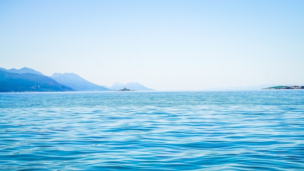 Free photo beautiful shot of sea with a mountain in the distance and a clear sky