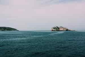 Free photo beautiful shot of the sea with rocks and cliffs under a cloudy sky