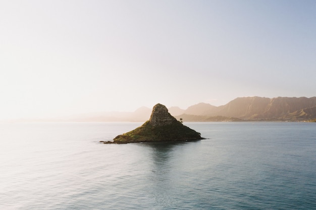 Beautiful shot of a small island in the center of the open sea with a scenery of sunrise