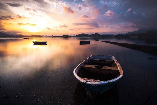 Beautiful shot of a small lake with a wooden rowboat in focus and amazing clouds in the sky