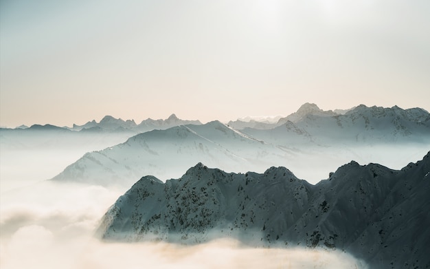 Beautiful shot of snowy mountain tops above the clouds with a clear sky