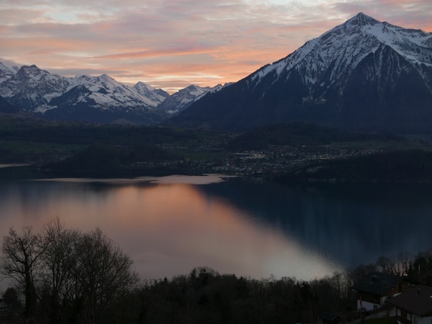 Beautiful shot of a steep mountain with white snow on the peak with a scenery of sunset in the sky