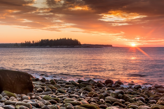 Beautiful shot of a stony  seashore  and the setting sun in the background