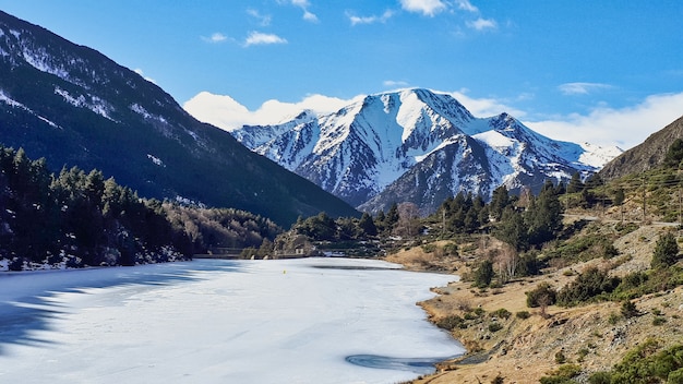 Beautiful shot of a summit with a frozen lake and a terrain with trees and shrubs