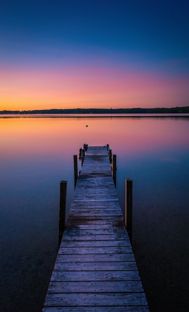 Free Photo beautiful shot of sunset colors in the horizon of a tranquil lake with a dock