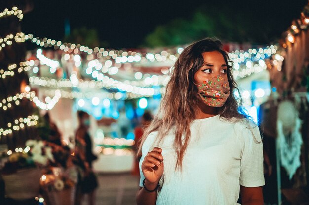 Beautiful shot of tanned European female wearing a floral mask at an amusement park