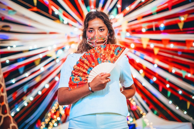 Beautiful shot of tanned European female wearing a floral mask at an amusement park