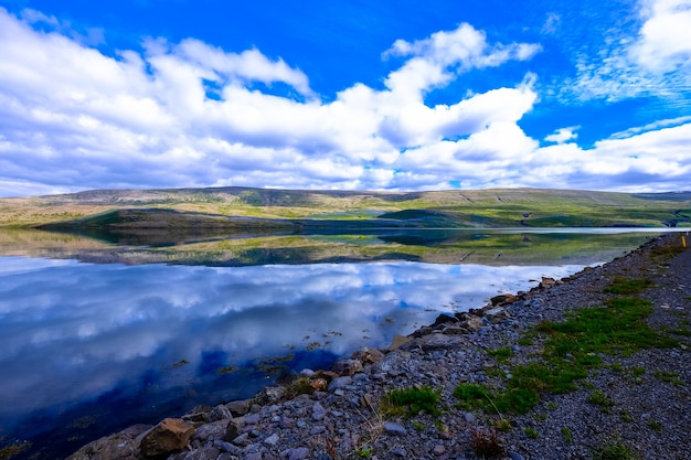 Beautiful shot of water near rocky shore and mountain in the distance with clouds in the sky