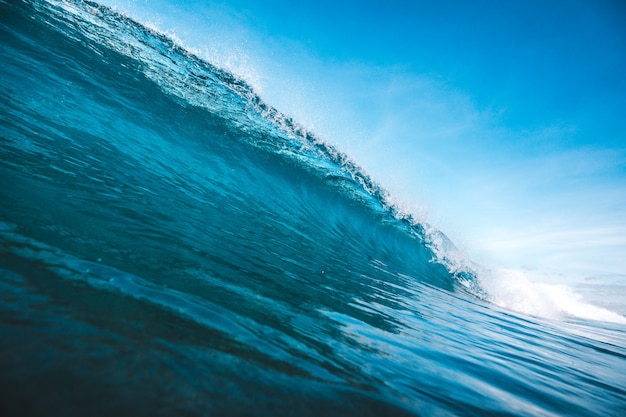 Beautiful shot of a wave taking shape under the clear blue sky captured in Lombok, Indonesia