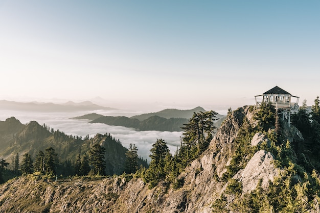 Beautiful shot of a white gazebo on top of the mountain near trees with a clear sky in background