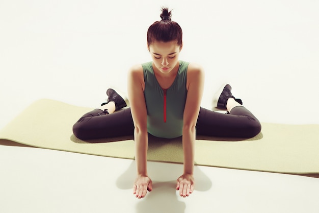 Free photo beautiful slim brunette doing some stretching exercises in a gym